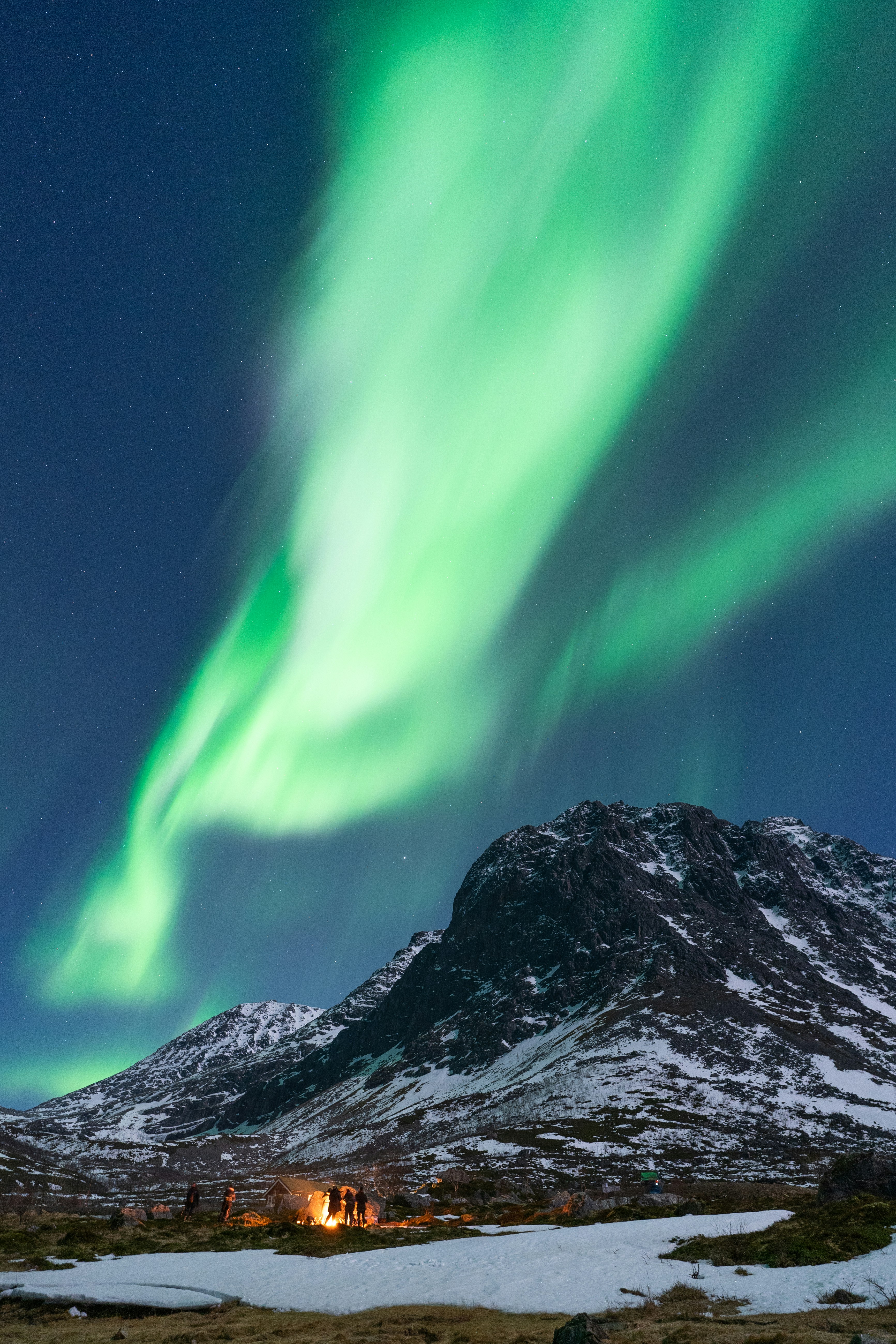 Green aurora borealis over a snowy mountain landscape in Norway